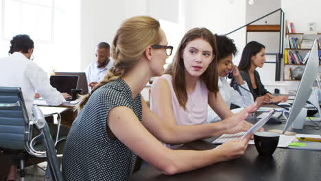 woman training new employee in an open plan office, slo mo