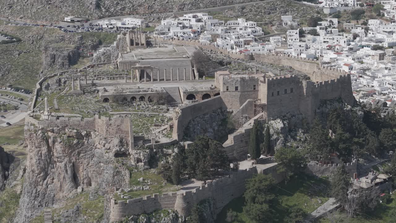 Orbit drone view of the Acropolis of Lindos creating parallax effect with the whitewashed houses. Ungraded clip. Shot with 3x telephoto lens. D-Log M profile
