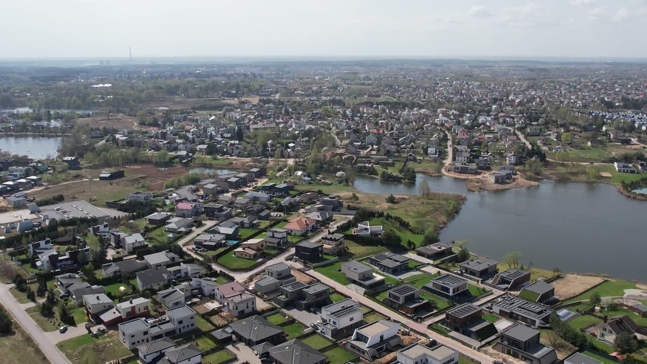 Drone lentää järvenrantamaiseman yllä Vilnan laitamilla kohti kaukana siintävää kaupunkia