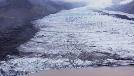 massive kvíarjökull glacier tongue on slope of mountain in iceland, cloudy