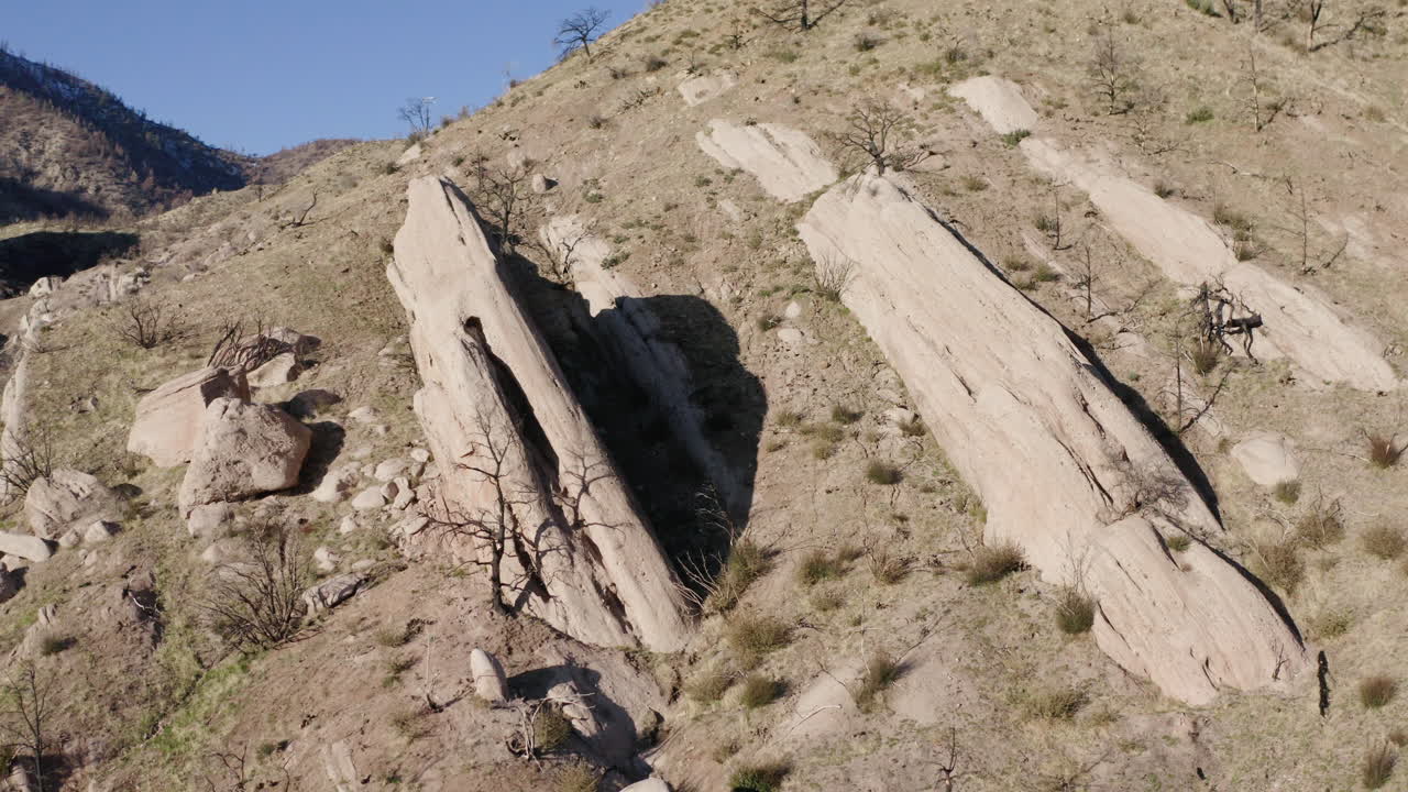 Large rock formations on a dry, rocky hillside with sparse vegetation