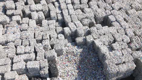 Aerial-view-overlooking-large-garbage-cubes,-sunny-day-at-a-junkyard