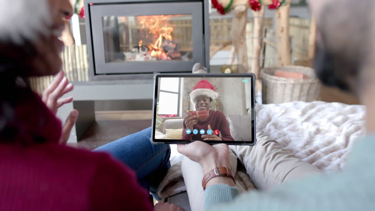 Coppia felice e diversa e un amico maschio che fanno una videochiamata di Natale su tablet, al rallentatore.