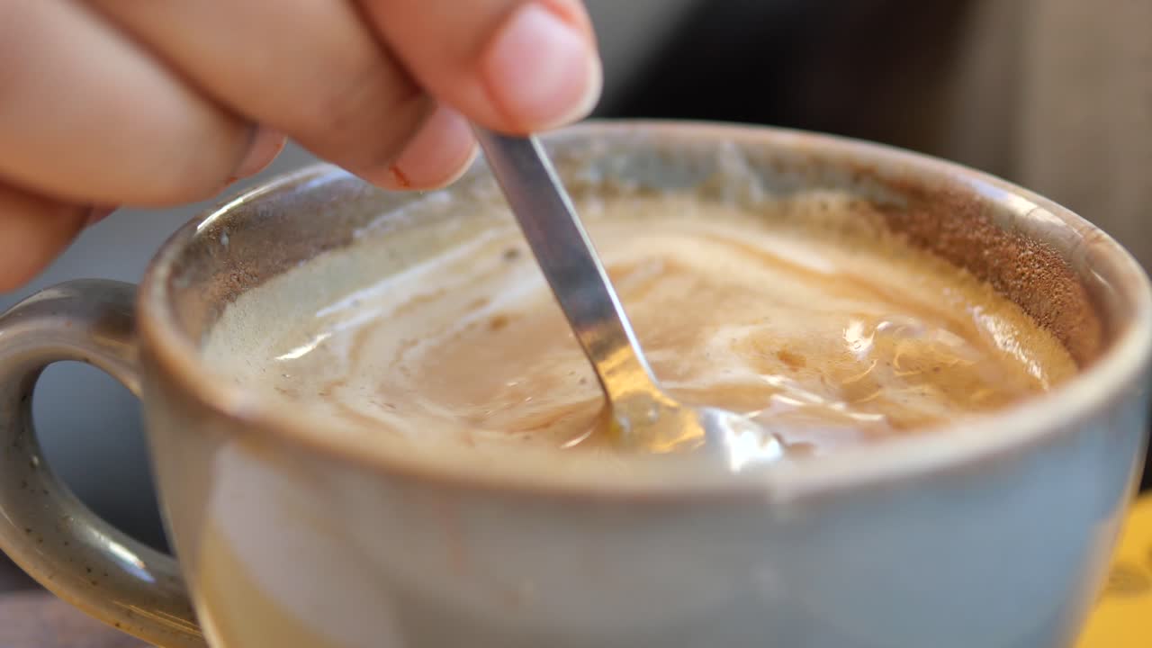 Close-up of a cup of coffee being stirred with a spoon