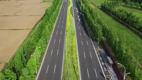 Aerial-photography-of-empty-long-city-road-lined-with-green-trees-on-side,-adding-to-the-serene,-tranquil-atmosphere-of-the-scenery