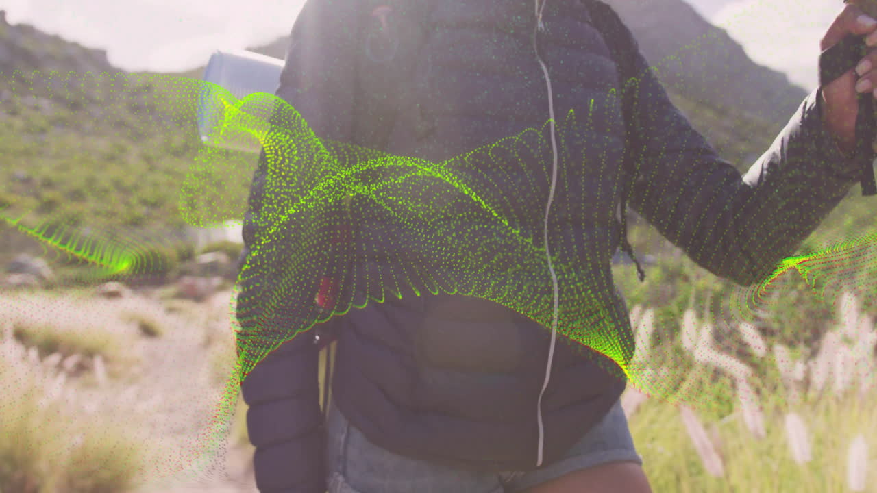 Woman wearing jacket gripping pole on mountain trail showing green data wave overlay for technology