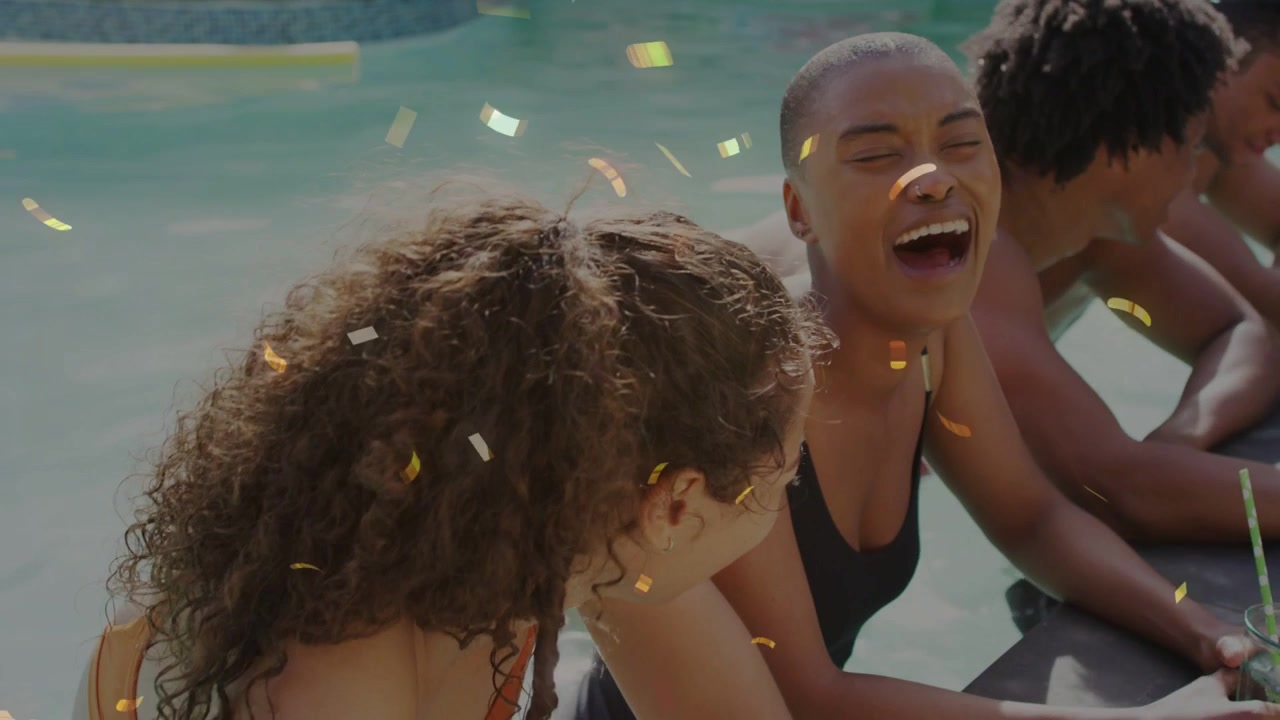 Four adults leaning on pool edge socializing, confetti releasing and sparking center woman laughing