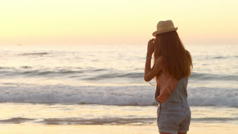 mujer tomando una foto con una cámara en la playa 4k