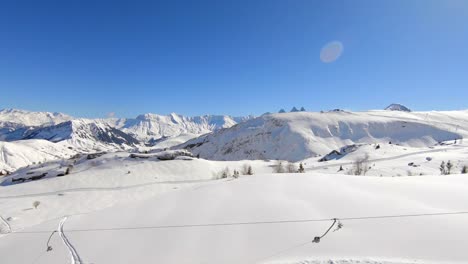 droneshot over a skilift with skiers and snowboarders in a snowy winter mountain landscape, in the les sybelles ski resort in the french alps