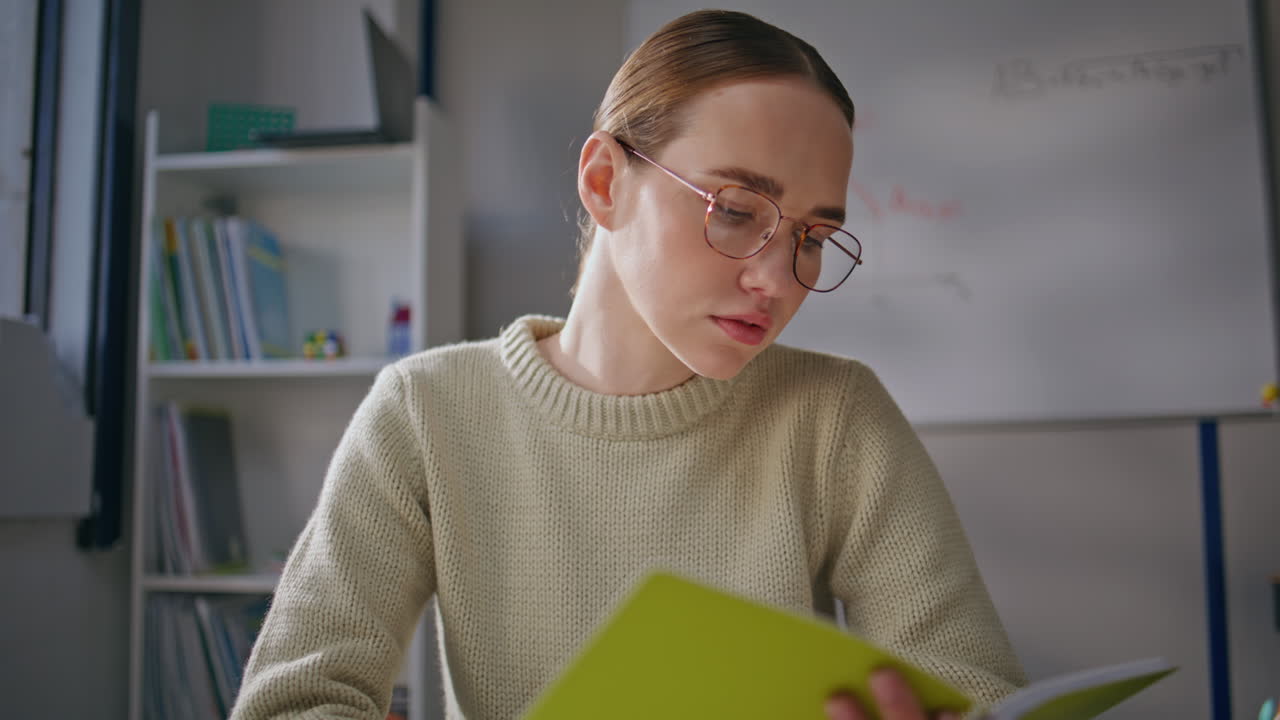 Serious teacher working classroom closeup. Woman in glasses checking homework