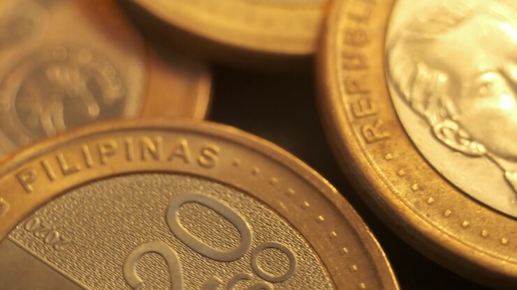 Primo piano estremo di una moneta filippina da venti pesos accanto al ritratto di un'altra moneta.
