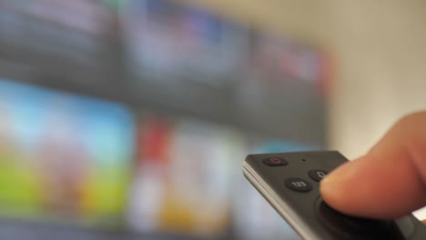 man watching smart tv and using modern black remote controller, blurred tv in the background. close up view - dci 4k video