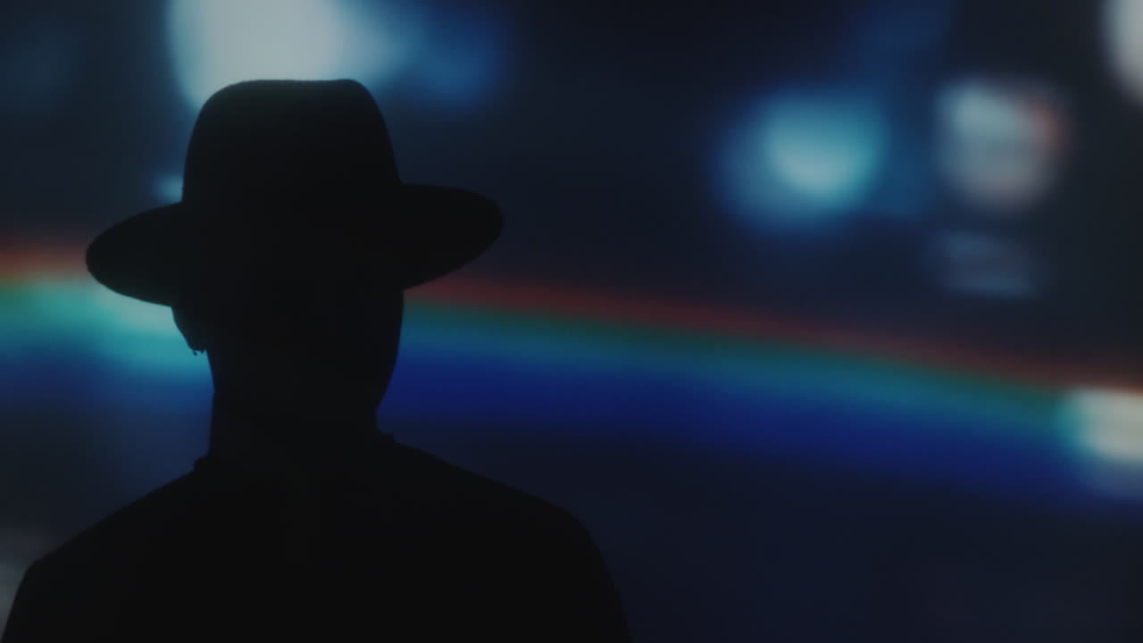 Silhouette of Man in Hat in Room with Rainbow Projection