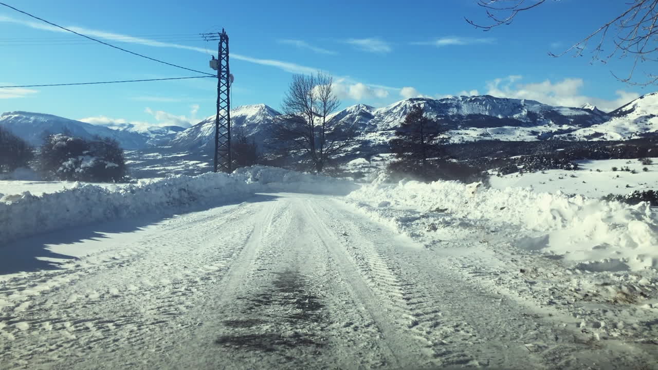 The cold wind blowing snow over the road high up in the mountains