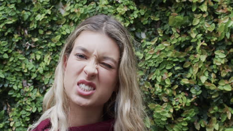 Portrait-of-happy-biracial-woman-with-blonde-hair-making-faces-in-garden,-slow-motion