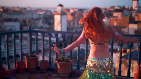 Hermosa-Bailarina-Del-Vientre-Haciendo-Un-Movimiento-De-Cabeza-Al-Atardecer-Actuando-En-Una-Azotea-En-Marruecos