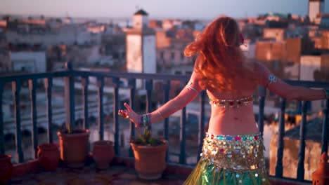 beautiful belly dancer doing a head toss at sunset performing on a rooftop in morocco