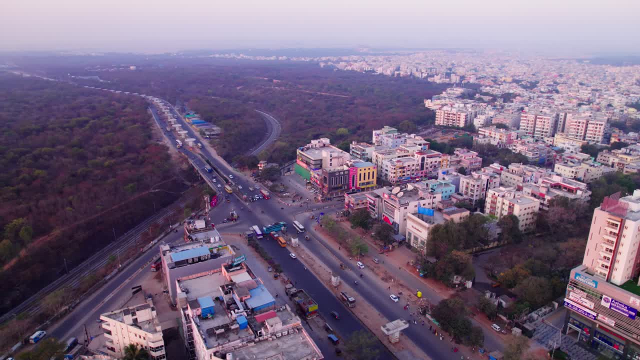 Suchitra circle with Hyderabad Metropolitan Development Authority Urban Forest, and crowded buildings at suchitra, hyderabad, telangana, india. day time, semi orbit, drone shot, 4k.