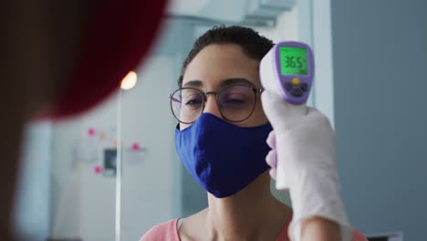 Mujer-Caucásica-Con-Mascarilla-Midiendo-Su-Temperatura-En-Una-Oficina-Moderna