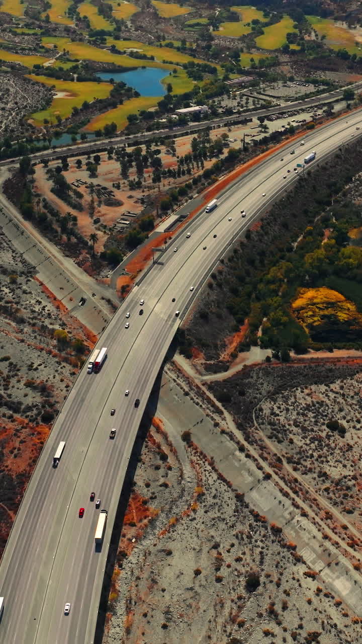 Rocky landscape with some islands of greenery. Multi-lane highway with transport moving by. Top view. Vertical video