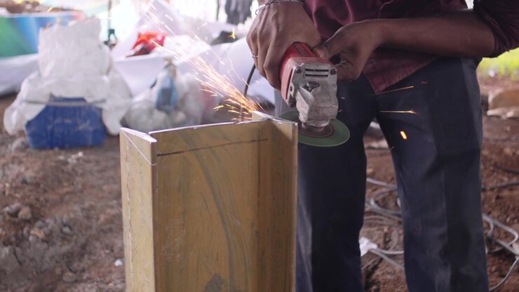 He is cutting a large iron rod with a grinding machine closeup view