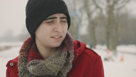 person in bonnet and scarf on blurry winter background during snowy daylight