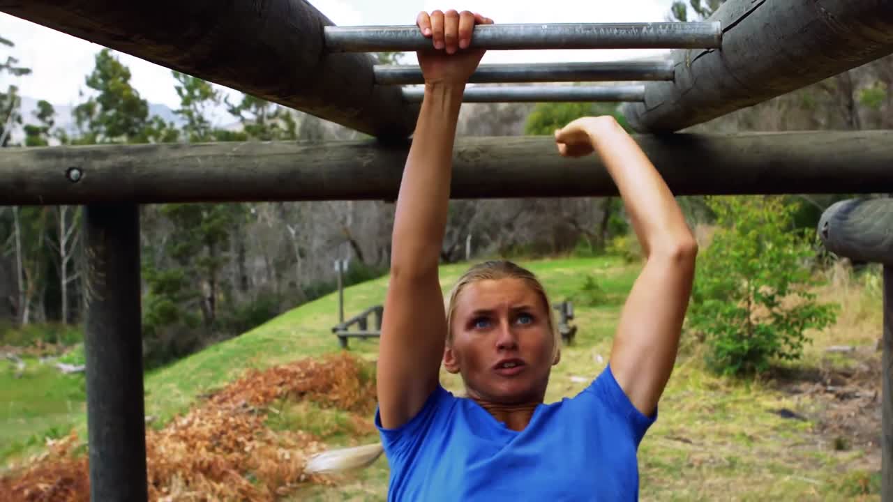 mujer cruzando las barras de monos durante el curso de obstáculos