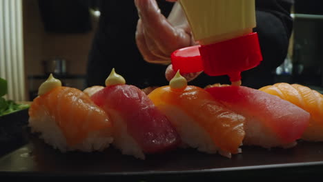 chef adding sauce to fresh nigiri sushi