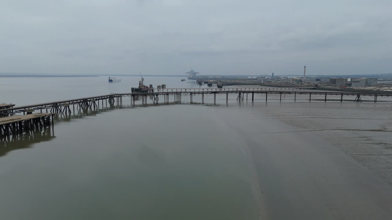 Aerial drone view of large piers with gas terminal pipelines on the River Thames at Canvey Island, UK, showing fuel storage and maritime loading operations
