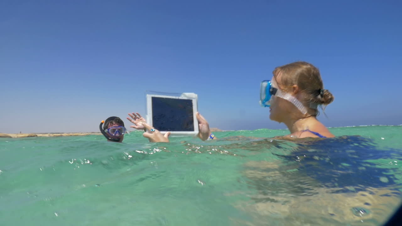 mujer y hombre en el mar haciendo fotos de vacaciones con el bloc