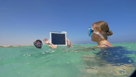 woman and man in the sea making vacation photos with pad