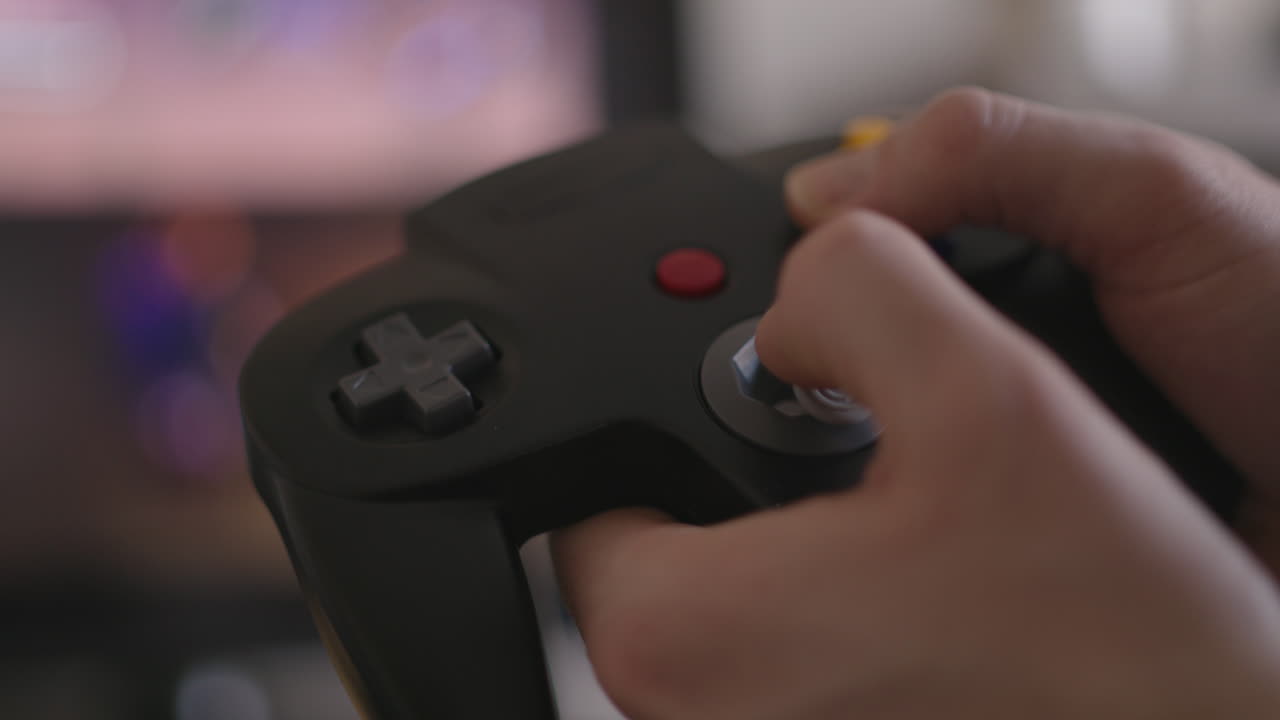 primo piano delle mani che giocano a un classico controller per videogiochi degli anni '90