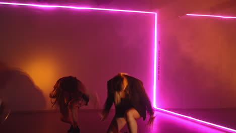 girls band dancing energetically in the studio. hip hop performers in the club with pink and yellow light.