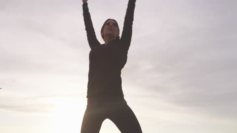 una mujer joven practicando yoga en el paseo marítimo