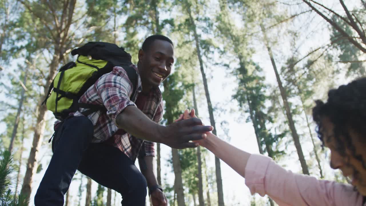 una pareja diversa sonriente cogida de las manos y caminando por el campo