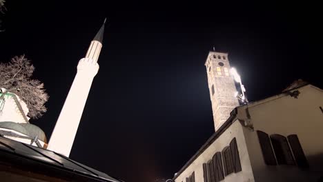 architectural detail of the old clock tower and minaret of gazi husrev beg mosque at night in sarajevo, bosnia and herzegovina