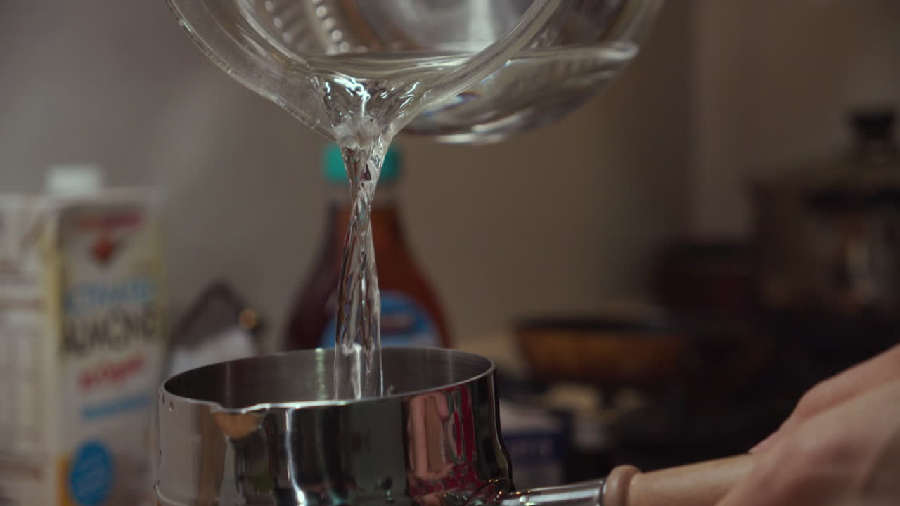 Water pours down from a glass pot into a small metal pan