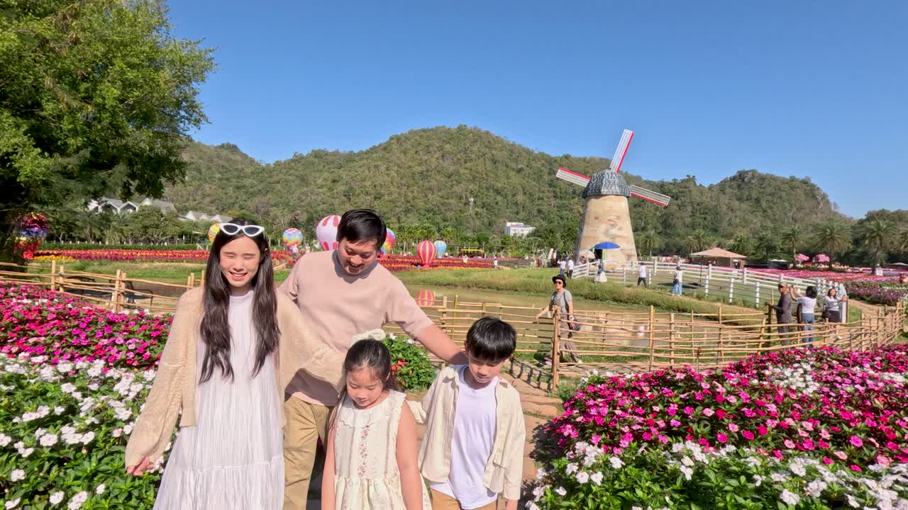 Una famiglia asiatica si gode una passeggiata in un colorato giardino fiorito con vista sulle montagne