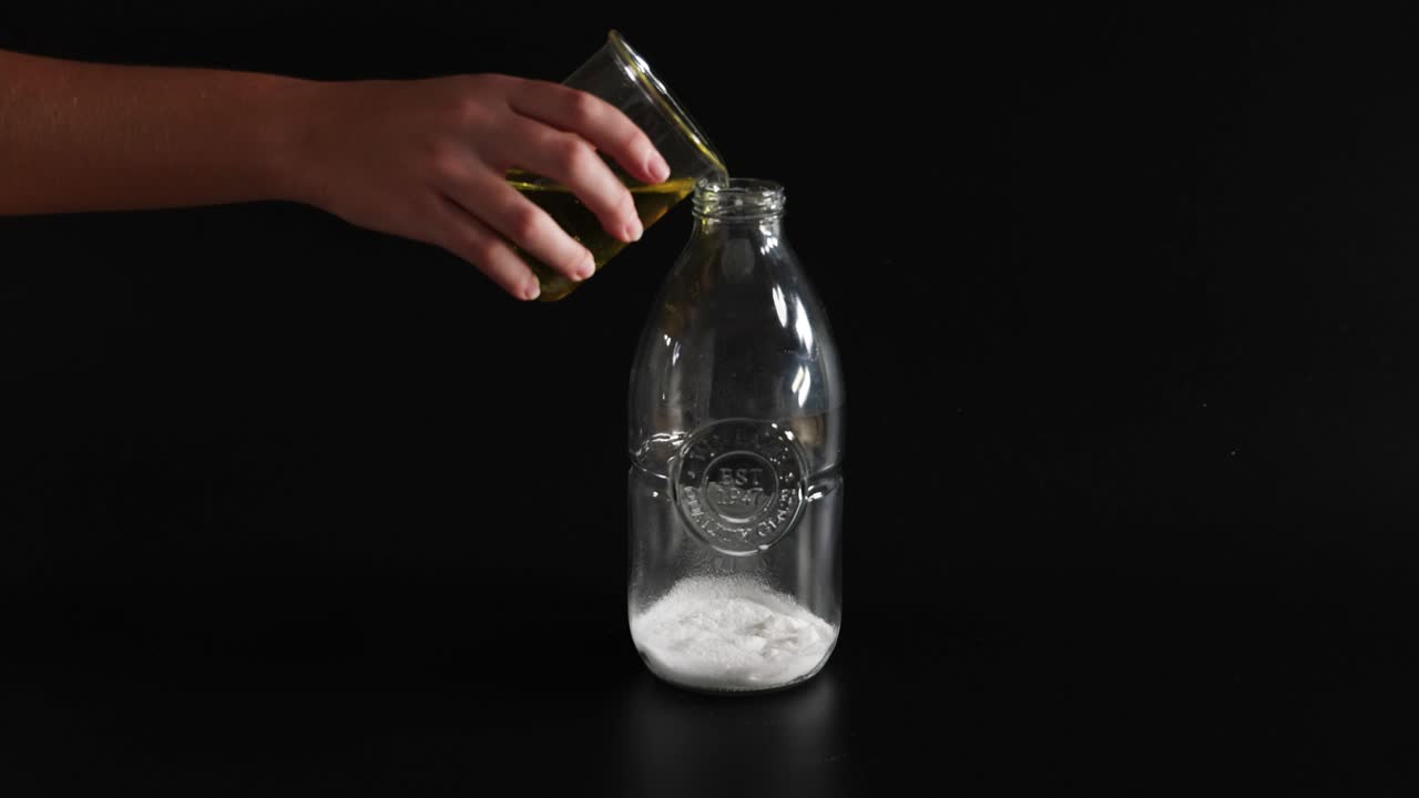 노란색 액체와 색 파우더가 병에서 반응합니다.