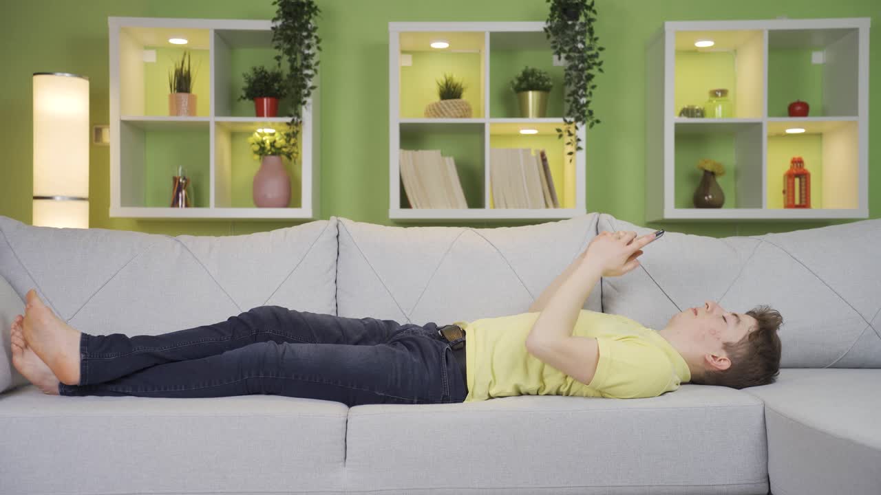 집에 있는 젊은 남자는 문자 메시지를 보내고 있습니다. 침체되고 불행합니다.