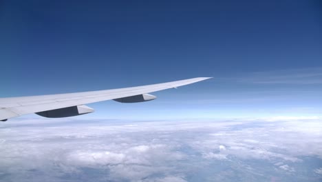 long slick airplane wing in flight, passenger view from the window