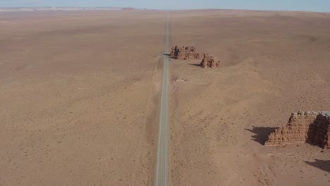 aerial view going over a desert road toward a small rock group formation off the side of a utah highway