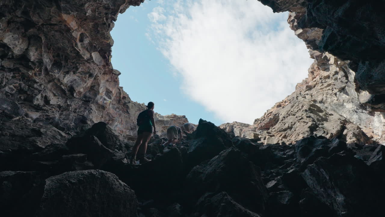 People Climbing Out of a Dark Cave Towards the Light