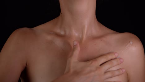 woman applying cream to shoulders and chest