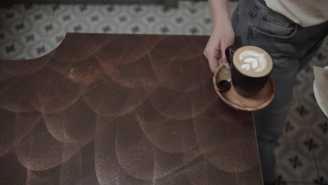 Top-view-of-barista-serving-fresh-coffee-and-piece-of-cake-in-bar,close-up-slow-motion