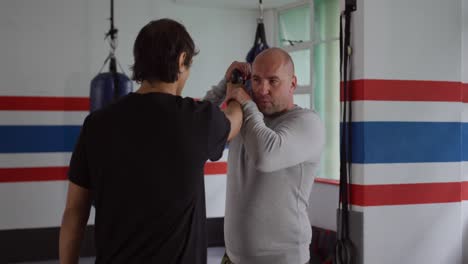 caucasian man learning self defense from trainer in gym