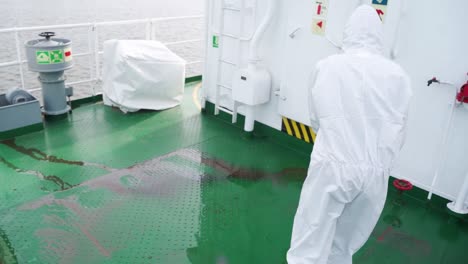 video en cámara lenta 4k hombre en bata blanca lavando agua de piso de metal que lava pisos de cubierta de barco de alta presión de una lavadora a presión