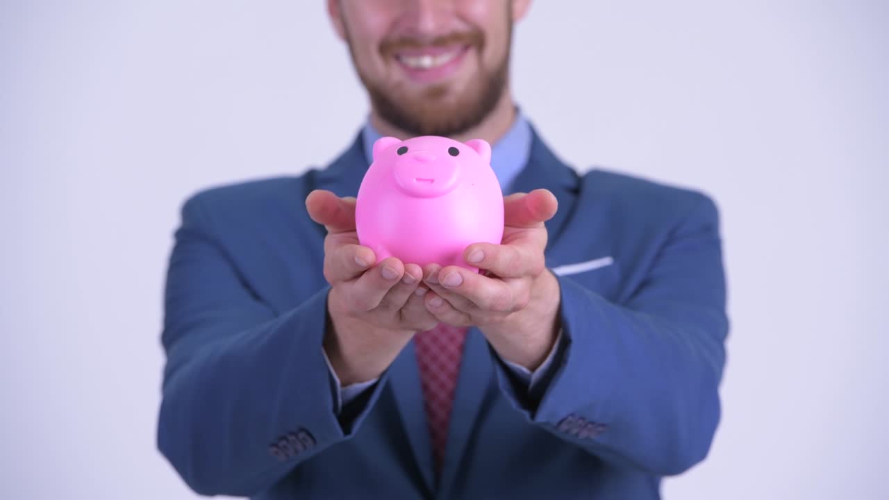 Portrait of happy bearded businessman with piggy bank