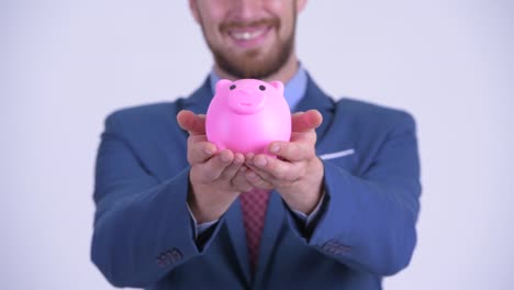 retrato de un feliz hombre de negocios barbudo con una alcancía