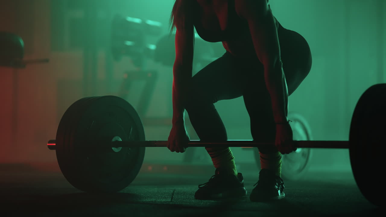 Slow motion: Athletic Beautiful Woman Does Overhead Deadlift with a Barbell in the Gym. Female Professional Bodybuilder Workout Weight Lift Exercises in the Authentic Sport Training Facility.